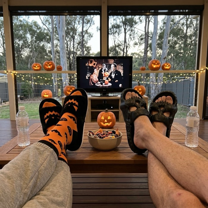 Couple's feet on a coffee table in pumpkin and skull Halloween slippers